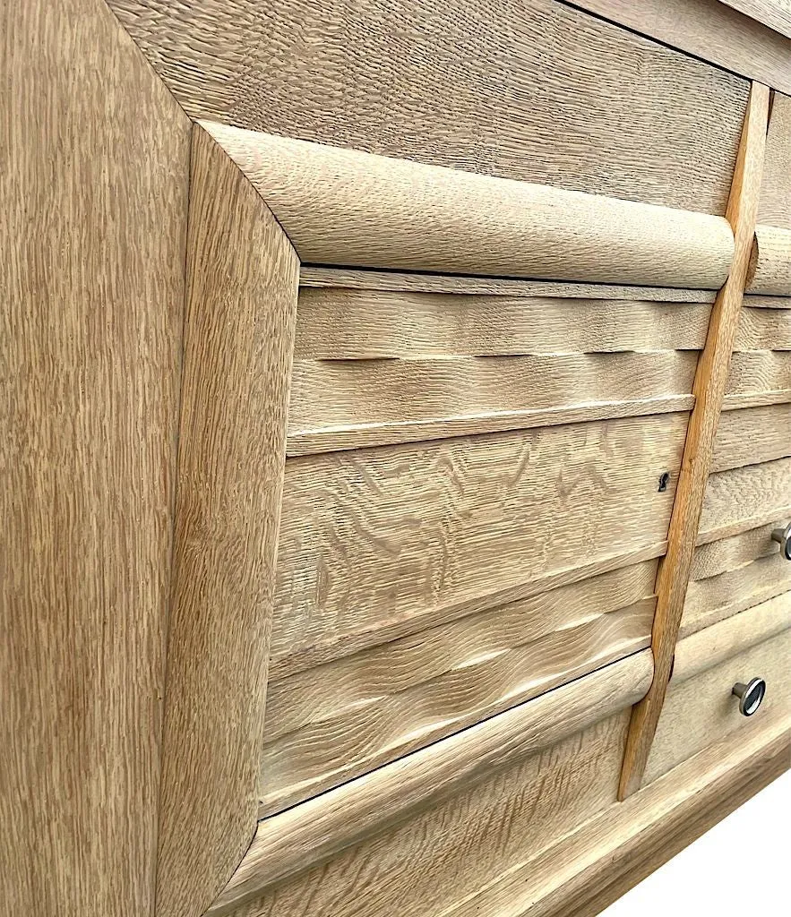A French 1940s bleached oak sideboard in the style of Charles Dudouyt with two doors and four central drawers and relief front design